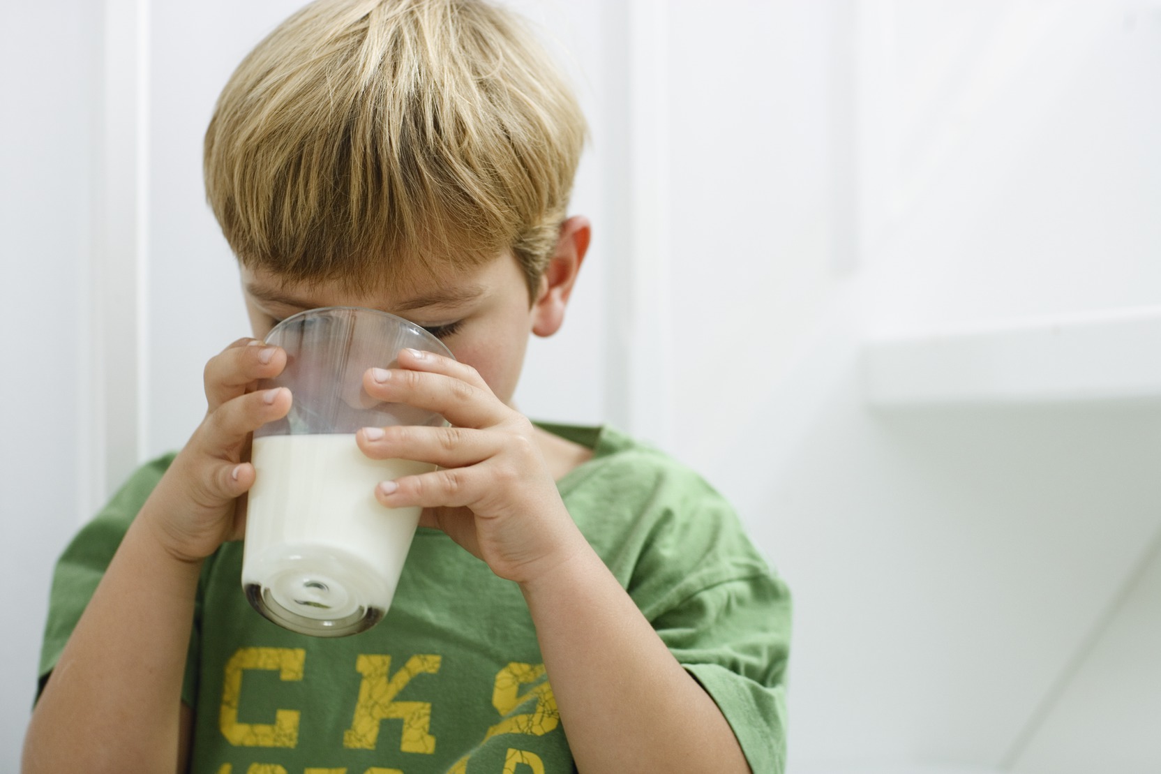 Boy drinking milk from a glass with both hands