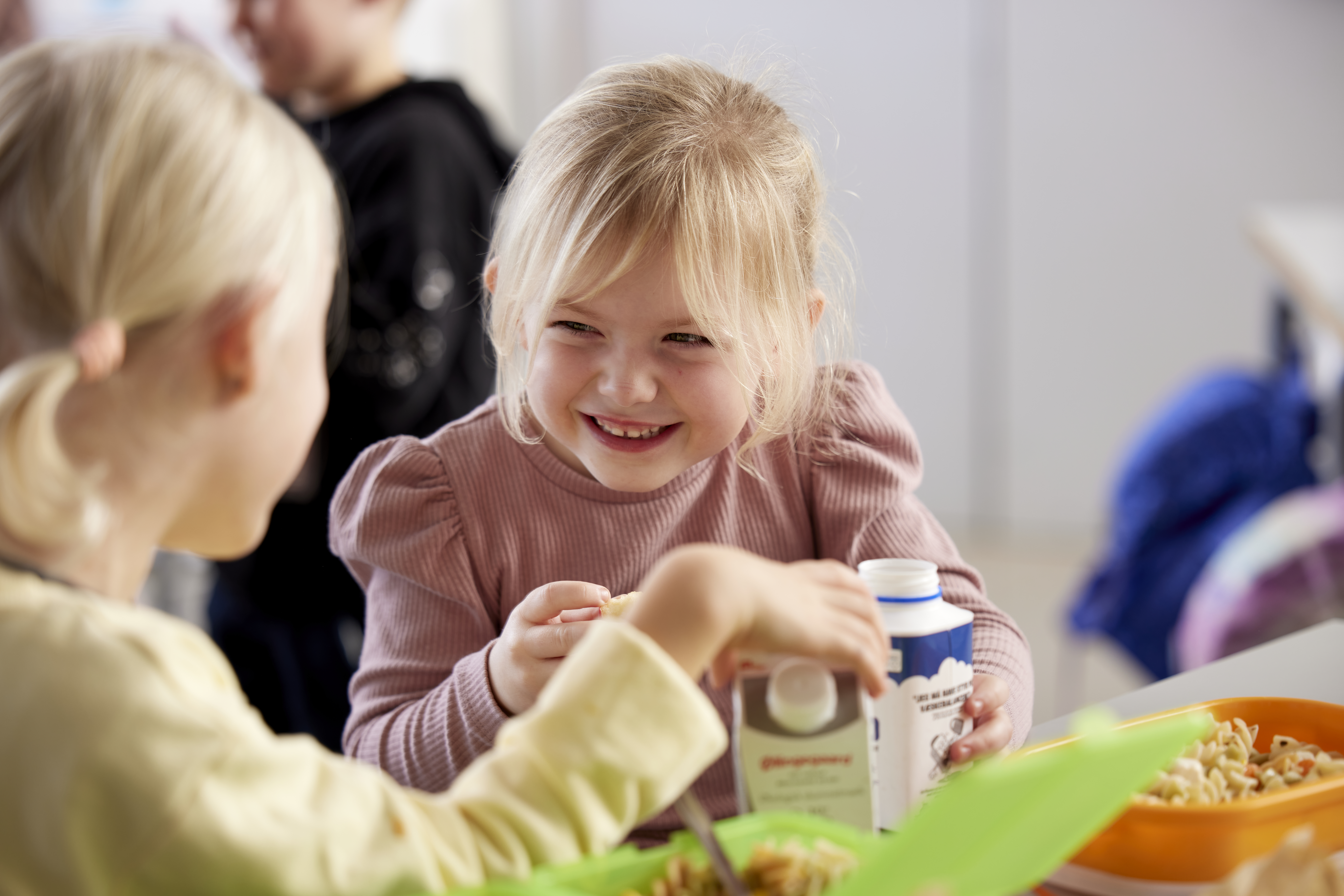 Little girl smniling at another girl at lunch in school