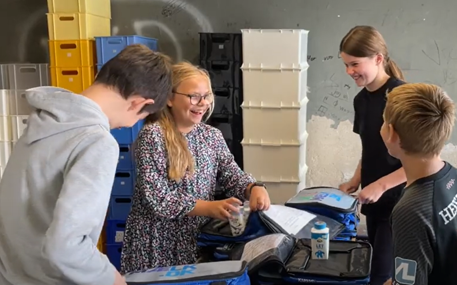 Group of children packing school milk for the rest of the school and smiling